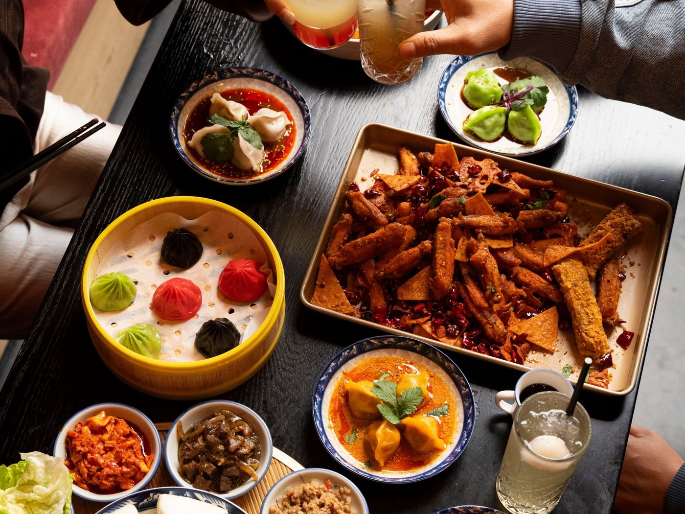 Friends clinking drinks over a bottomless dumpling table at Mr Hao